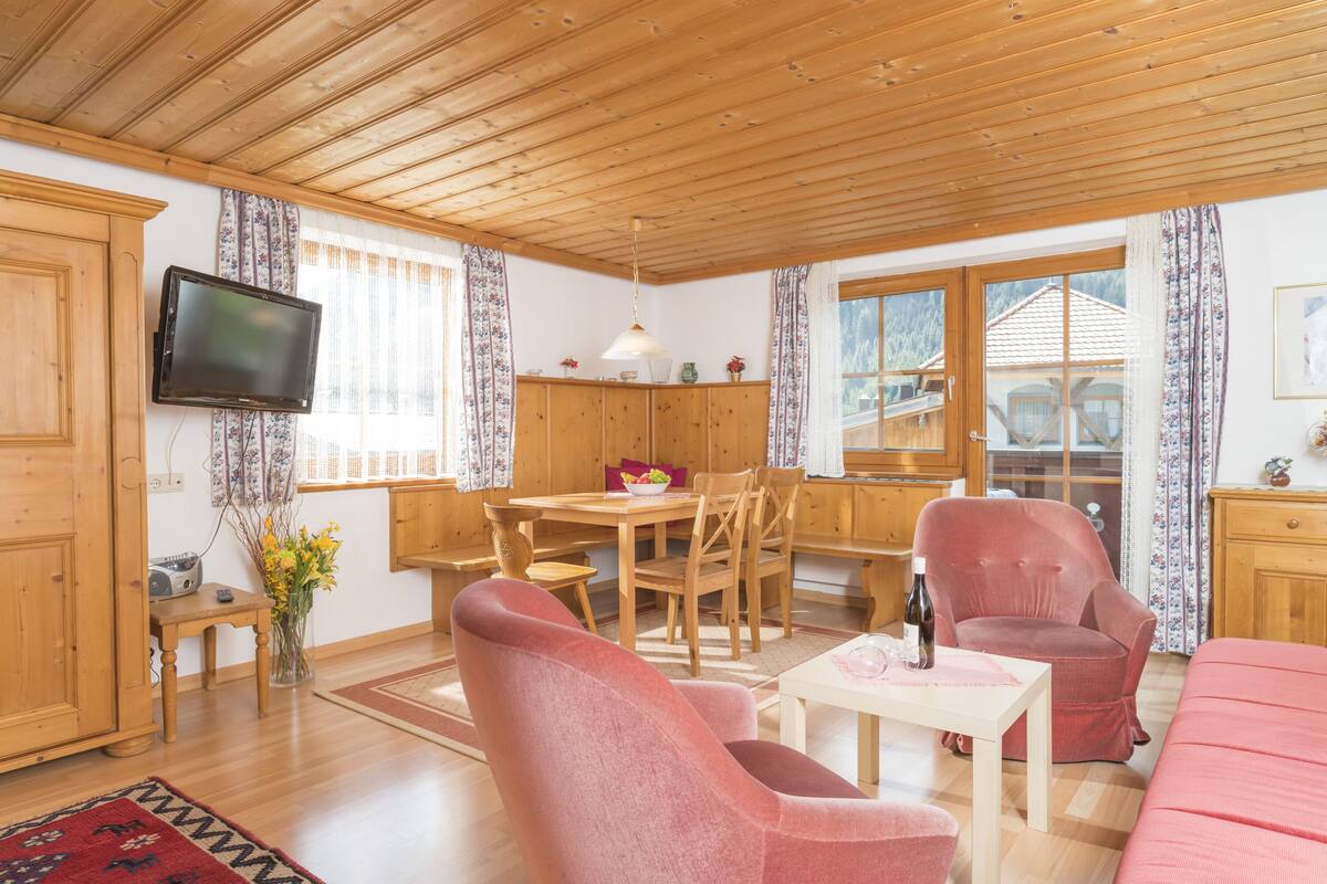 Ein gemütliches Zimmer mit Holzmöbeln, einem Fernseher und einem Essbereich.