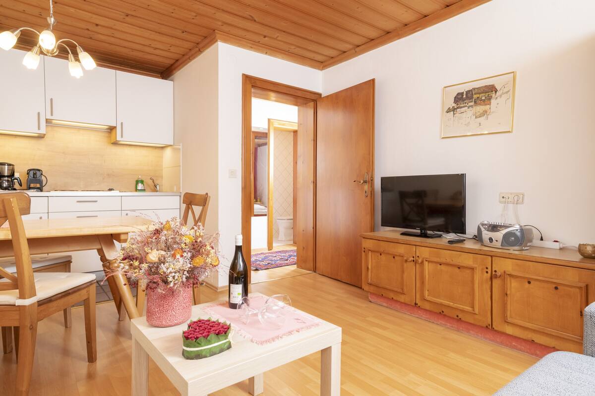 Eine moderne Küche mit weißen Schränken, einem Holzespeisetisch und einem Fernseher auf einem Holzkasten.