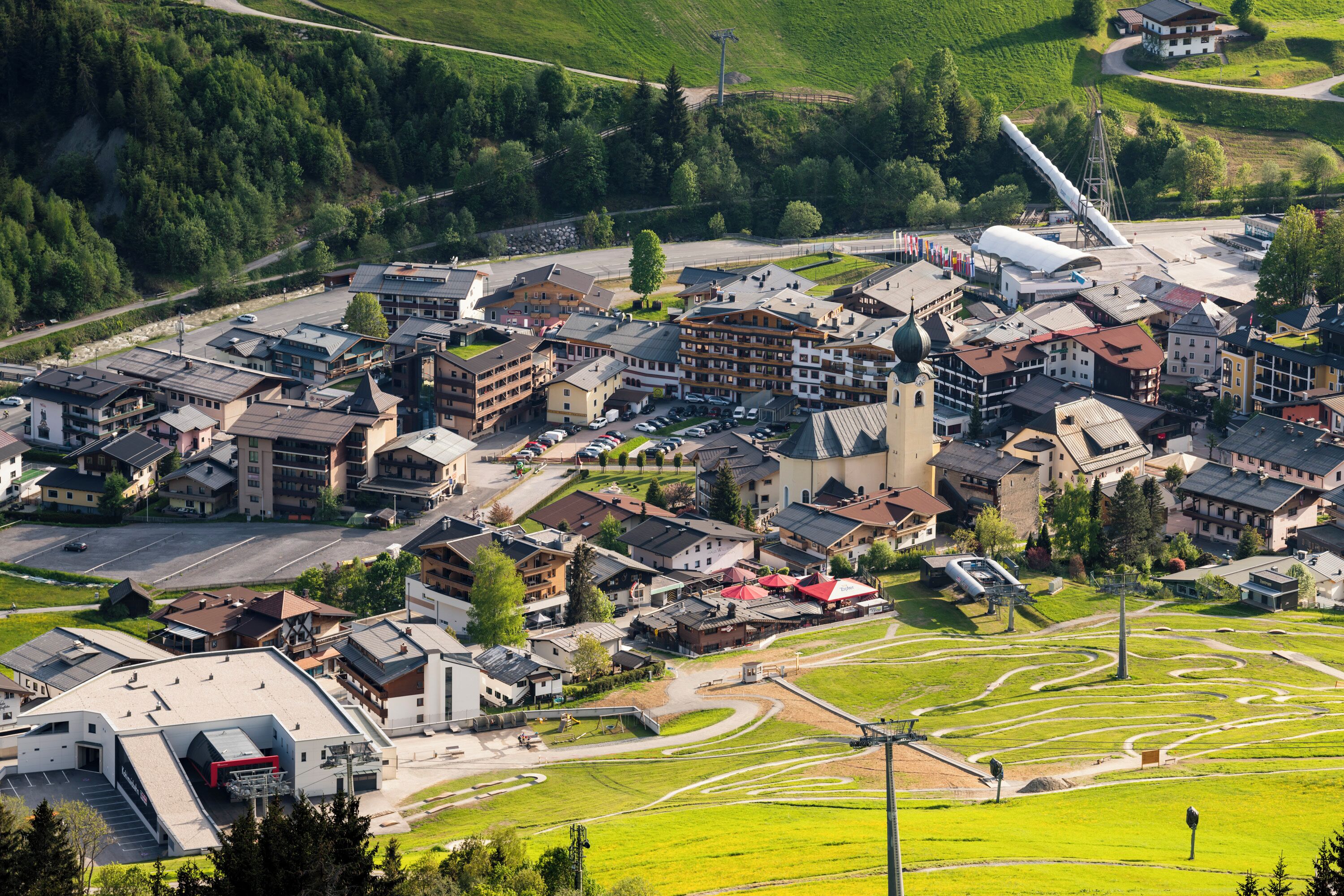 Une ville où se côtoient des bâtiments traditionnels et modernes, avec une église au centre et un télésiège.