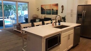 Eine moderne Küche mit einer zentralen Kochinsel, weißen Schränken und einem Edelstahl-Kühlschrank.