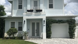 Ein zweistöckiges Haus mit Garage, Veranda und einem kleinen Garten.