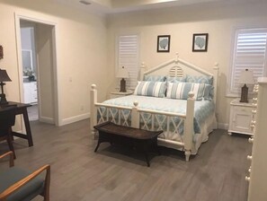 Une chambre à coucher avec un lit, des tables de chevet, une chaise et une petite table.