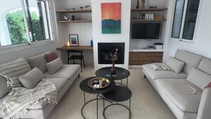 A modern living room with two sofas, a coffee table, and a fireplace. There are bookshelves and a TV mounted on the wall. - Fantastic Villa in Binixica,  pool, A/C, close to beaches (Binixiquer)