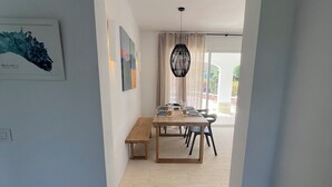 A dining area with a wooden table, chairs, and a hanging light fixture. - Fantastic Villa in Binixica,  pool, A/C, close to beaches (Binixiquer)
