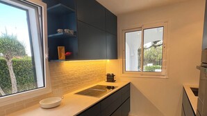 A modern kitchen with dark cabinets, a white countertop, and a window with a view of greenery. - Fantastic Villa in Binixica,  pool, A/C, close to beaches (Binixiquer)