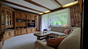 Un salon comprenant un canapé, une table basse et un meuble de rangement en bois avec un téléviseur.