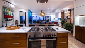 A modern kitchen with a central island, built-in oven, and a dining area with a view. - Fully remodeled 12 stories up! First floor retreat!! (Puerto Vallarta)