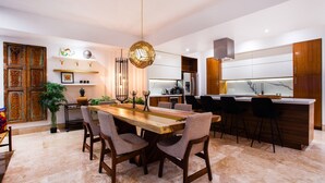 A modern kitchen with a wooden dining table, chairs, and a hanging light fixture. - Fully remodeled 12 stories up! First floor retreat!! (Puerto Vallarta)