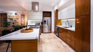 A modern kitchen with a central island, stainless steel appliances, wooden cabinets, and a marble countertop. - Fully remodeled 12 stories up! First floor retreat!! (Puerto Vallarta)