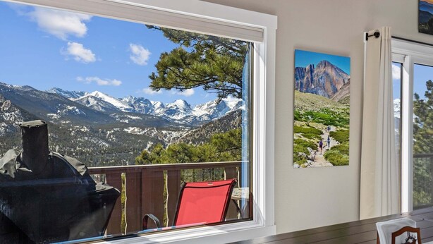 A room with a large window overlooking a mountainous landscape, a red chair, and a framed picture on the wall. - Destiny Vacation Home At Windcliff 3 Bedroom Home by RedAwning (Estes Park)