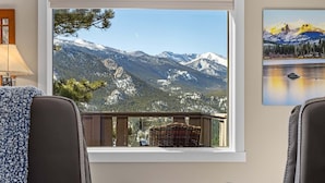 A room with a view of snow-capped mountains, a wicker basket, a glass table, and two leather chairs. - Destiny Vacation Home At Windcliff 3 Bedroom Home by RedAwning (Estes Park)