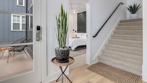 A modern interior with a staircase, a potted plant, and a view into a bedroom.