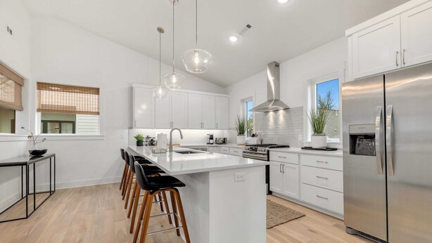 A modern kitchen with a central island, stainless steel appliances, and pendant lighting.