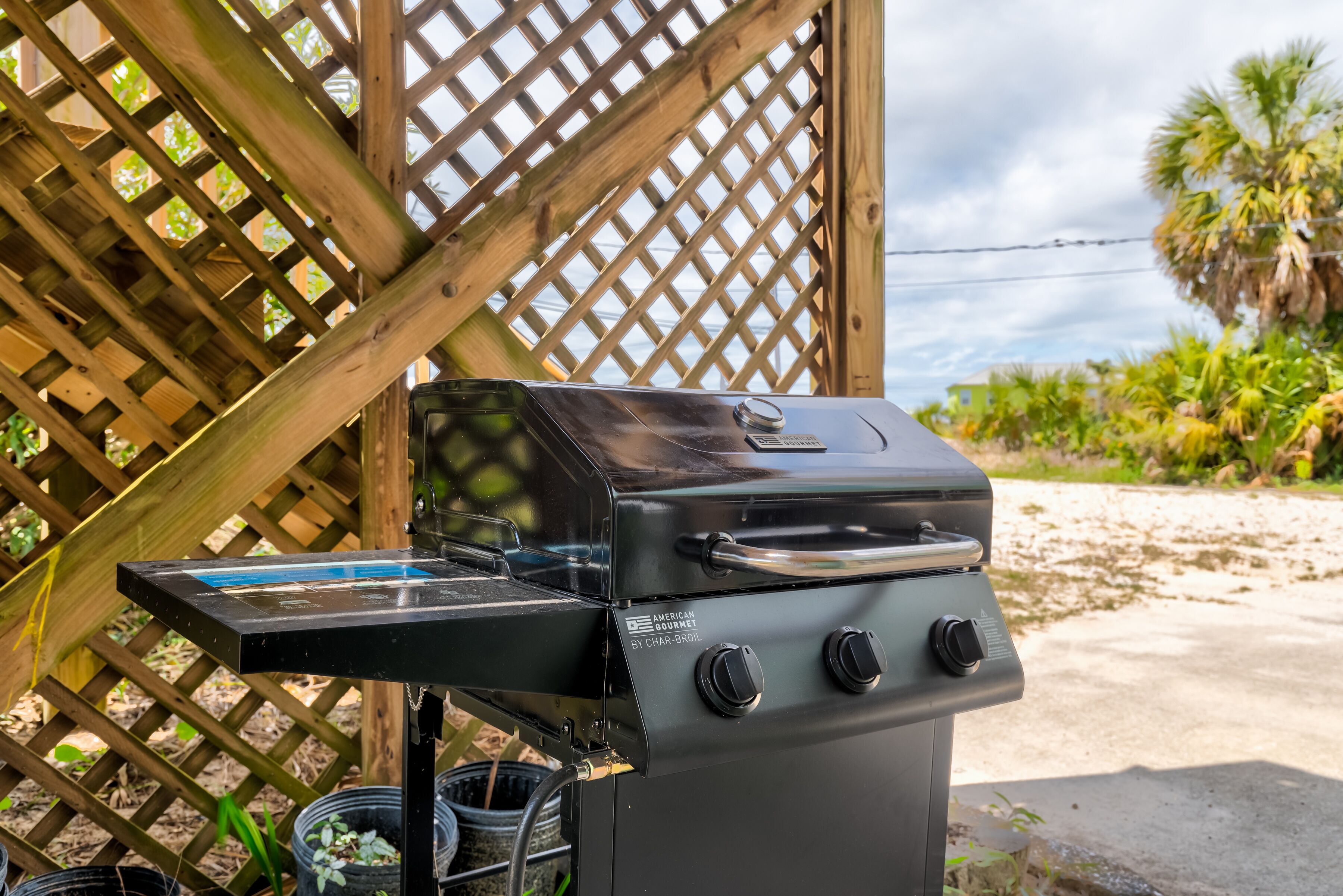 A charcoal grill with a digital display, set against a wooden lattice backdrop.
