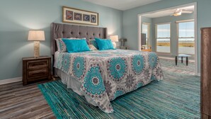 A bedroom with a bed, nightstands, a ceiling fan, and a view of the outdoors.