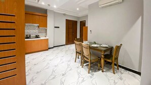 A dining area with a marble floor, wooden chairs, and a table set for four. - Heng Mohasal Apartment (Phnom Penh)