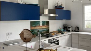 A modern kitchen with white countertops, a central island with a fruit bowl, blue cabinets, and pendant lights. - E Villa Clara, 600m de la mer, piscine (Saint-Denis-d´Oléron)