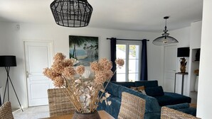 A dining area with a wooden table, wicker chairs, and a vase with dried flowers. - E Villa Clara, 600m de la mer, piscine (Saint-Denis-d´Oléron)