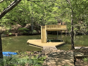 A wooden dock extending into a pond surrounded by dense forest.