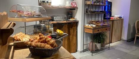 A breakfast buffet with bread, pastries, and a coffee station.