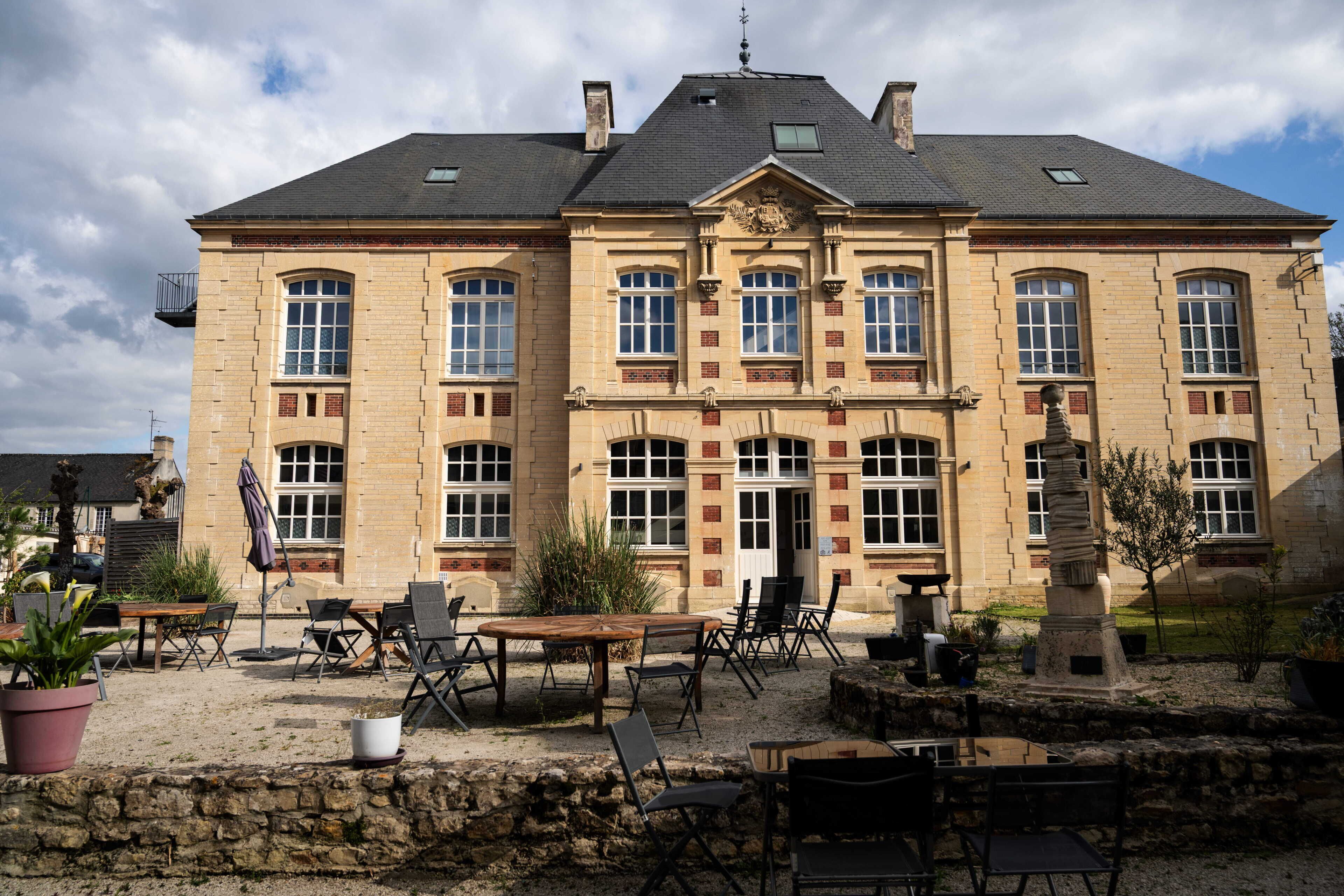Un grand bâtiment historique à la façade symétrique, doté de nombreuses fenêtres et d’une entrée centrale.
