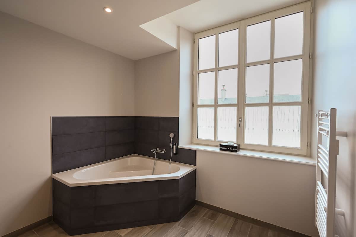 Un baño moderno con una bañera independiente, una ventana con persianas y un radiador.