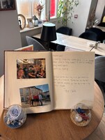 Un libro de visitas abierto con notas manuscritas y fotografías.