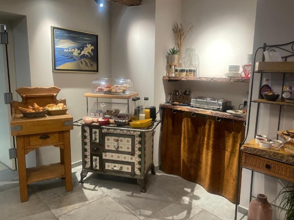 A kitchen with a wooden table, a vintage cabinet, and a shelf with food items.