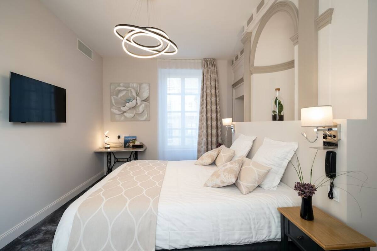 Una habitación de hotel moderna con una cama grande, un escritorio, un televisor de pantalla plana y un elemento decorativo en la pared.
