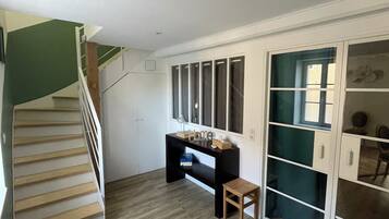 Una habitación con una escalera de madera, un escritorio con una computadora y un taburete pequeño.