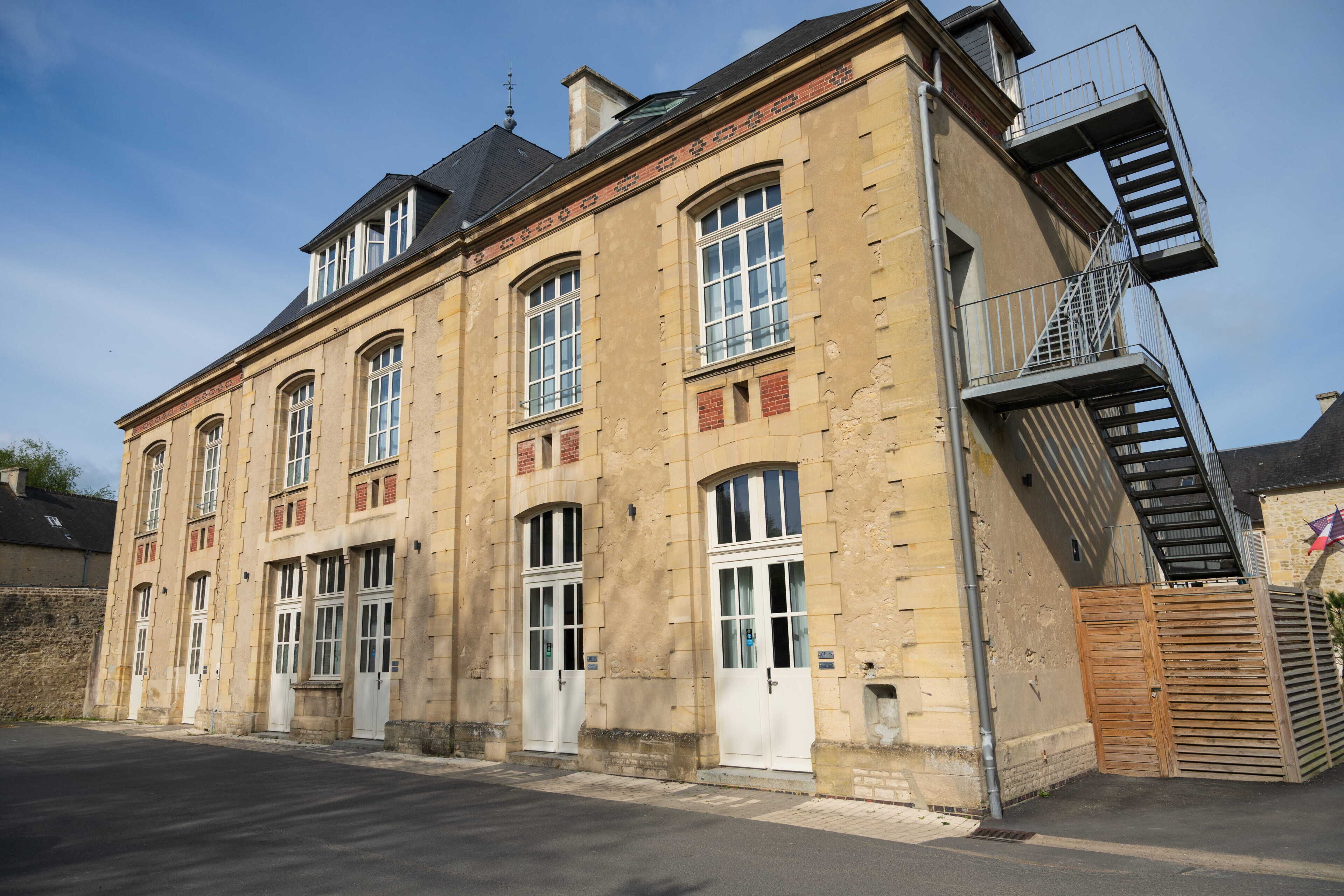 A historic building with multiple windows, a fire escape, and a gated entrance.