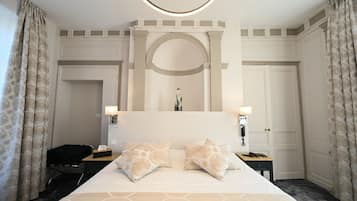 A hotel room with a large bed, two bedside lamps, a desk, and a chair.