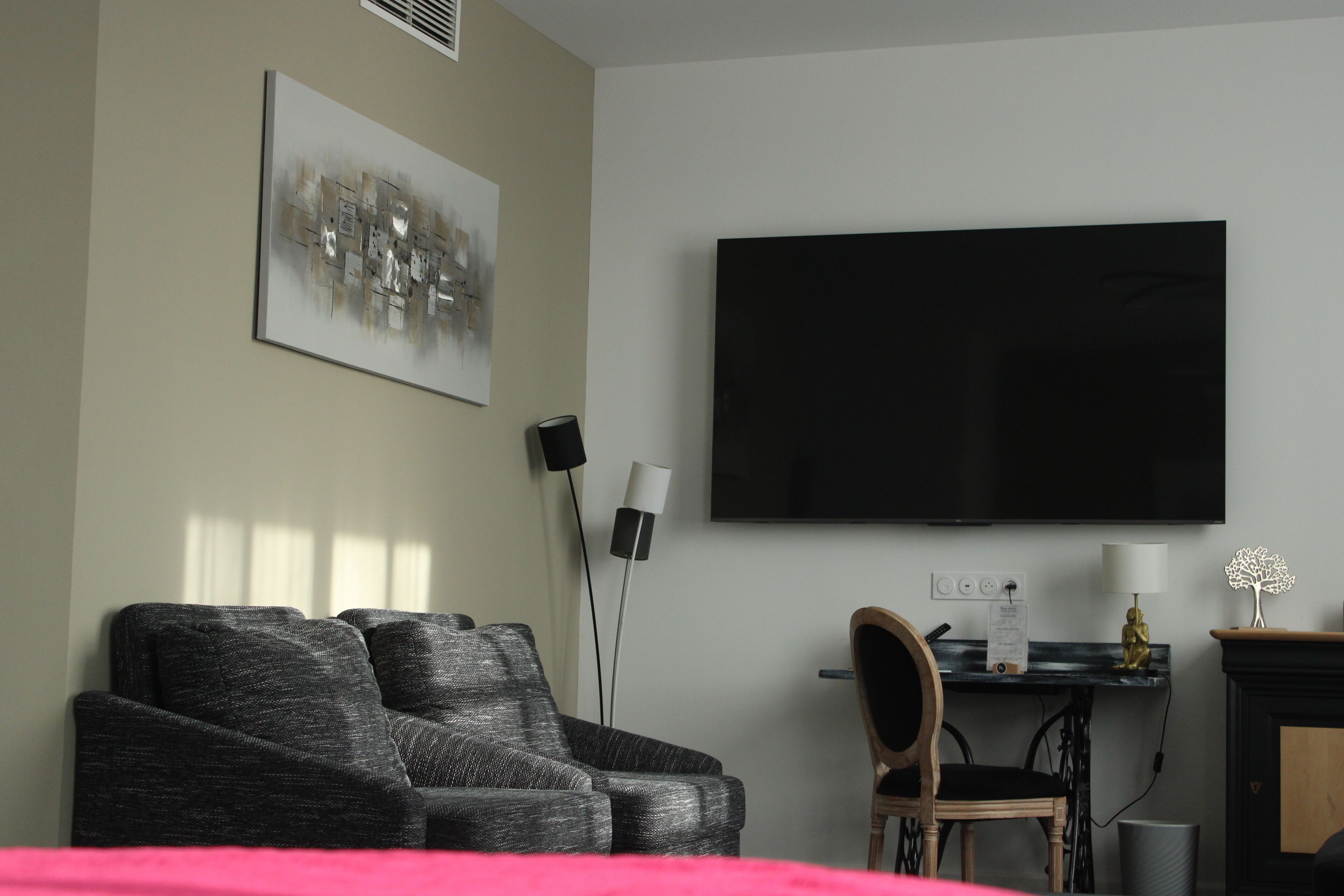 A modern living room with a large flat-screen TV, a sofa, a chair, and a fireplace.