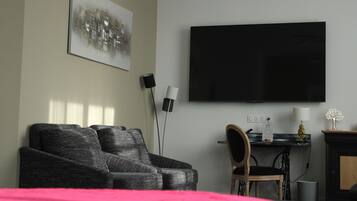 A modern living room with a large flat-screen TV, a sofa, a chair, and a fireplace.