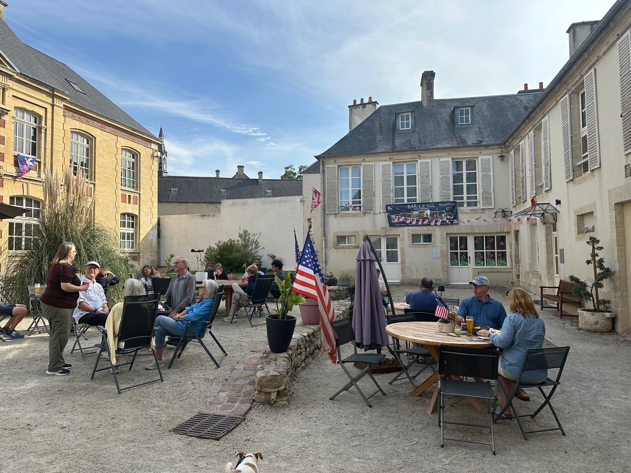 An outdoor patio area with tables and chairs, surrounded by buildings with a traditional architectural style.