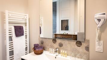 A bathroom with a white sink, a mirror, a towel rack, a hairdryer, and a basket of towels.