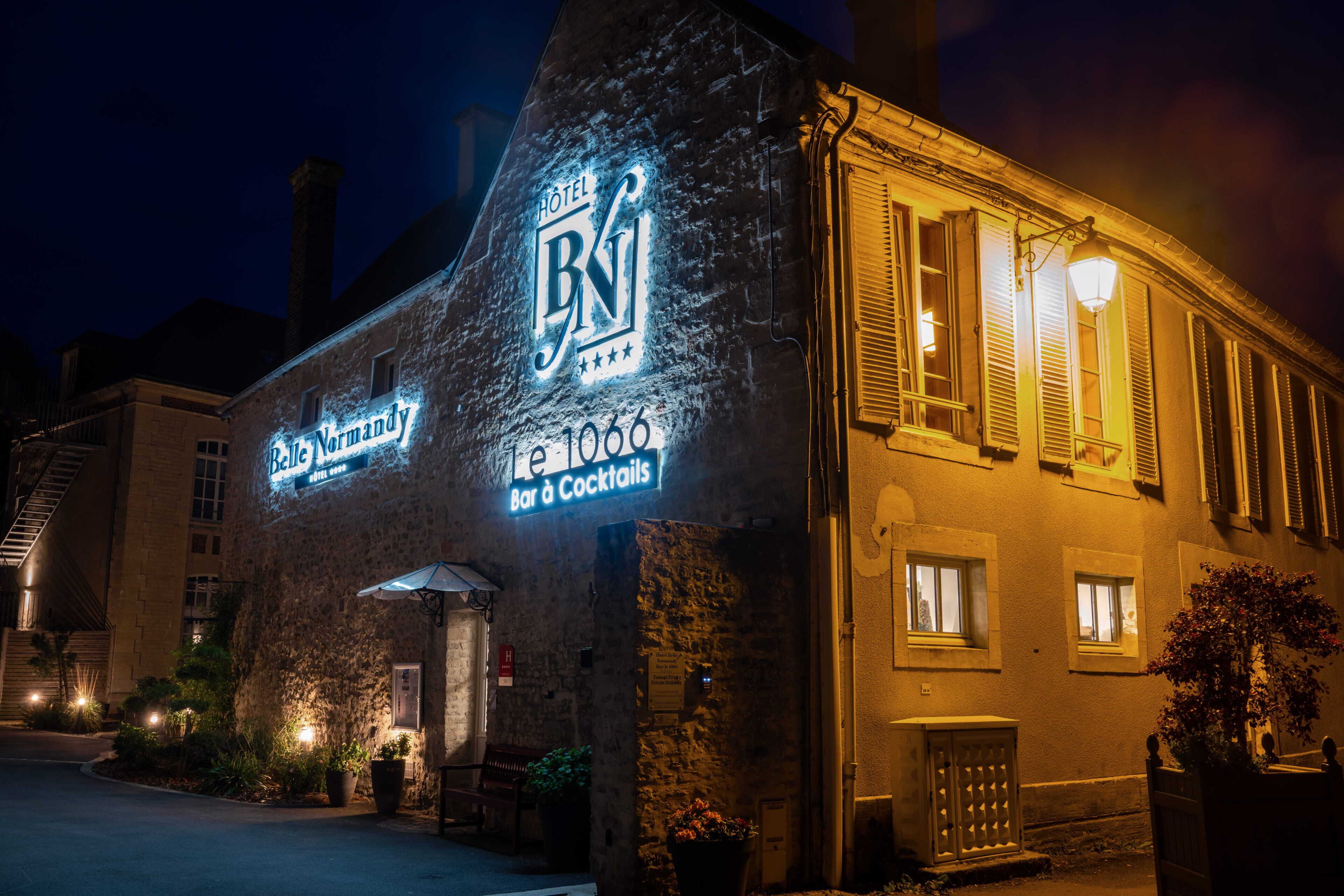 Een hotel met een gevel van natuursteen, verlichte signage en een bar/loungeruimte.