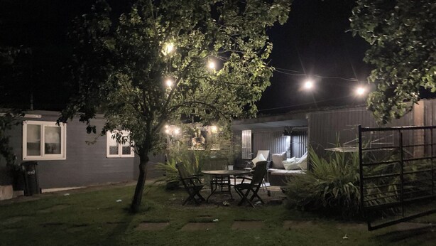 Een achtertuin met terras, tuinmeubilair en lichtjes.