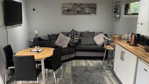 Een ruimtelijk ingerichte leefruimte met een bank, een eettafel en een keukenhoek.