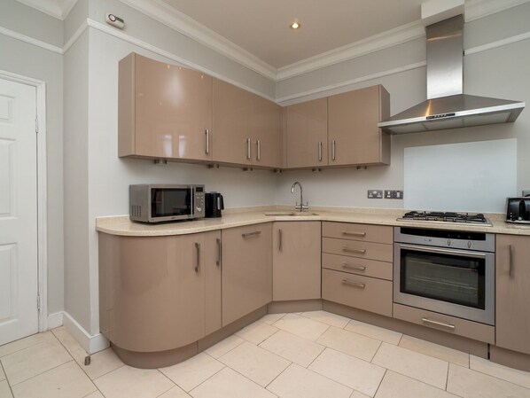 A modern kitchen with beige cabinets, a microwave, a coffee maker, a sink, a stove, and an oven. - Spacious 3 bed apartment in prime central location - Pass the Keys (Bath)