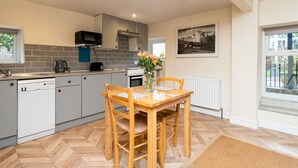 A modern kitchen with grey cabinets, a microwave, a kettle, and a dining table with chairs. - Lovely 1 bed apartment with free parking - Pass the Keys (Bath)