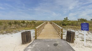 Un muelle de madera que conduce a una zona de playa, con un cartel sobre mejoras del muelle pesquero del Parque Little Lagoon.