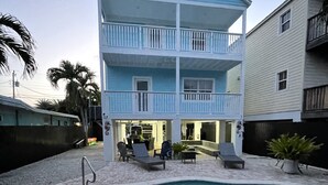 A two-story building with a pool, outdoor seating, and a palm tree. - Tropical Retreat in the Heart of the Keys (Marathon)