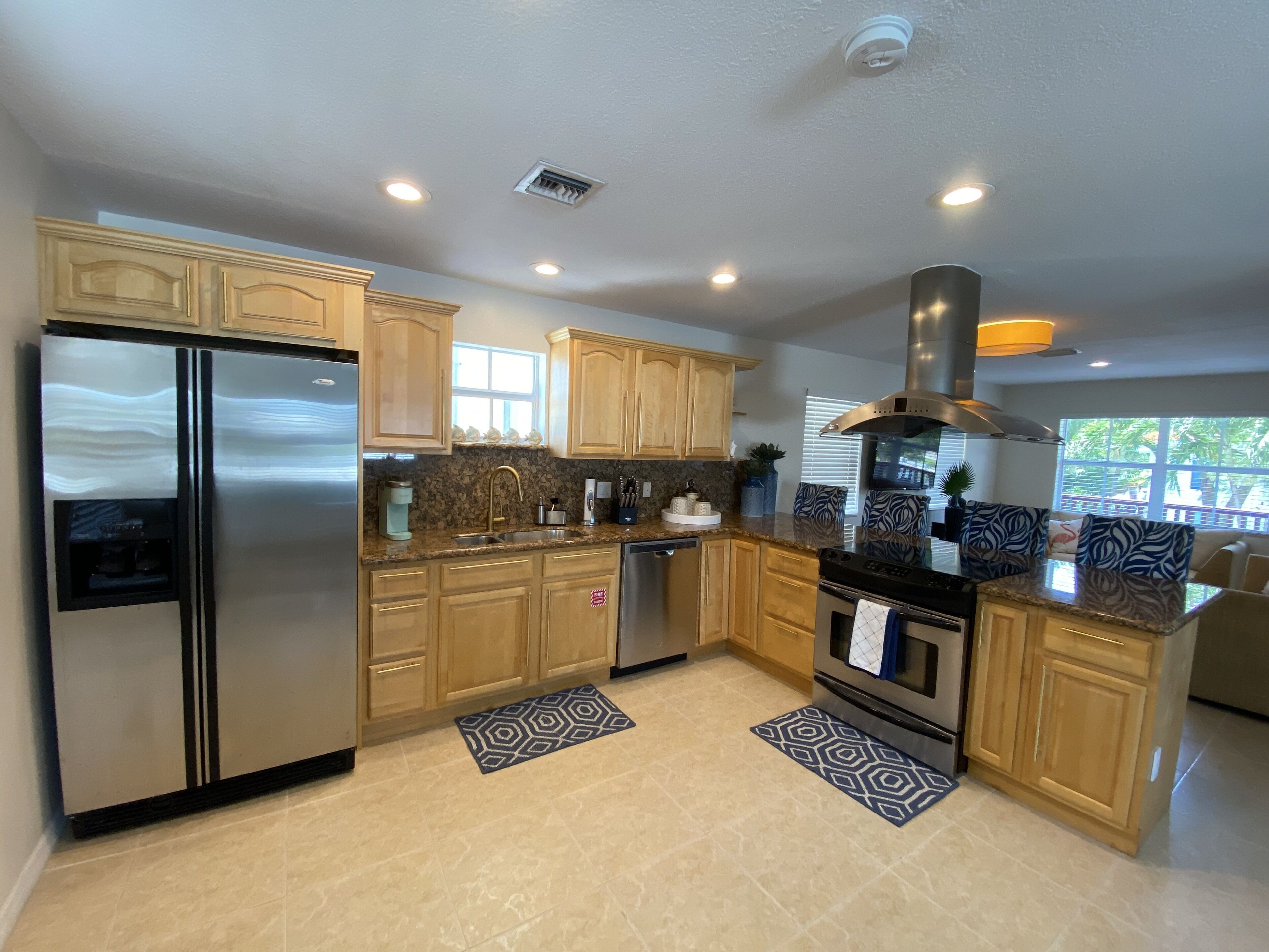 A modern kitchen with wooden cabinets, stainless steel appliances, and a large window providing natural light. - Tropical Retreat in the Heart of the Keys (Marathon)