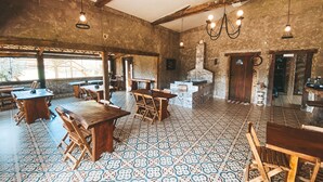 A rustic restaurant interior with wooden tables and chairs, patterned floor tiles, exposed wooden beams, and hanging light fixtures. - COMPLEXO JARDIM SECRETO (Santa Barbara)