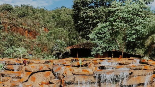 A natural pool with clear turquoise water, surrounded by rocky formations and a large tree. - COMPLEXO JARDIM SECRETO (Santa Barbara)
