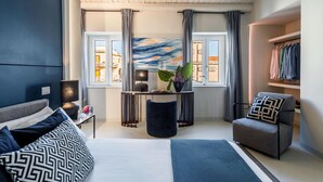 A modern bedroom with a bed, bedside table, lamp, chair, and a view of the city through large windows. - Casa San Lio (Noto)