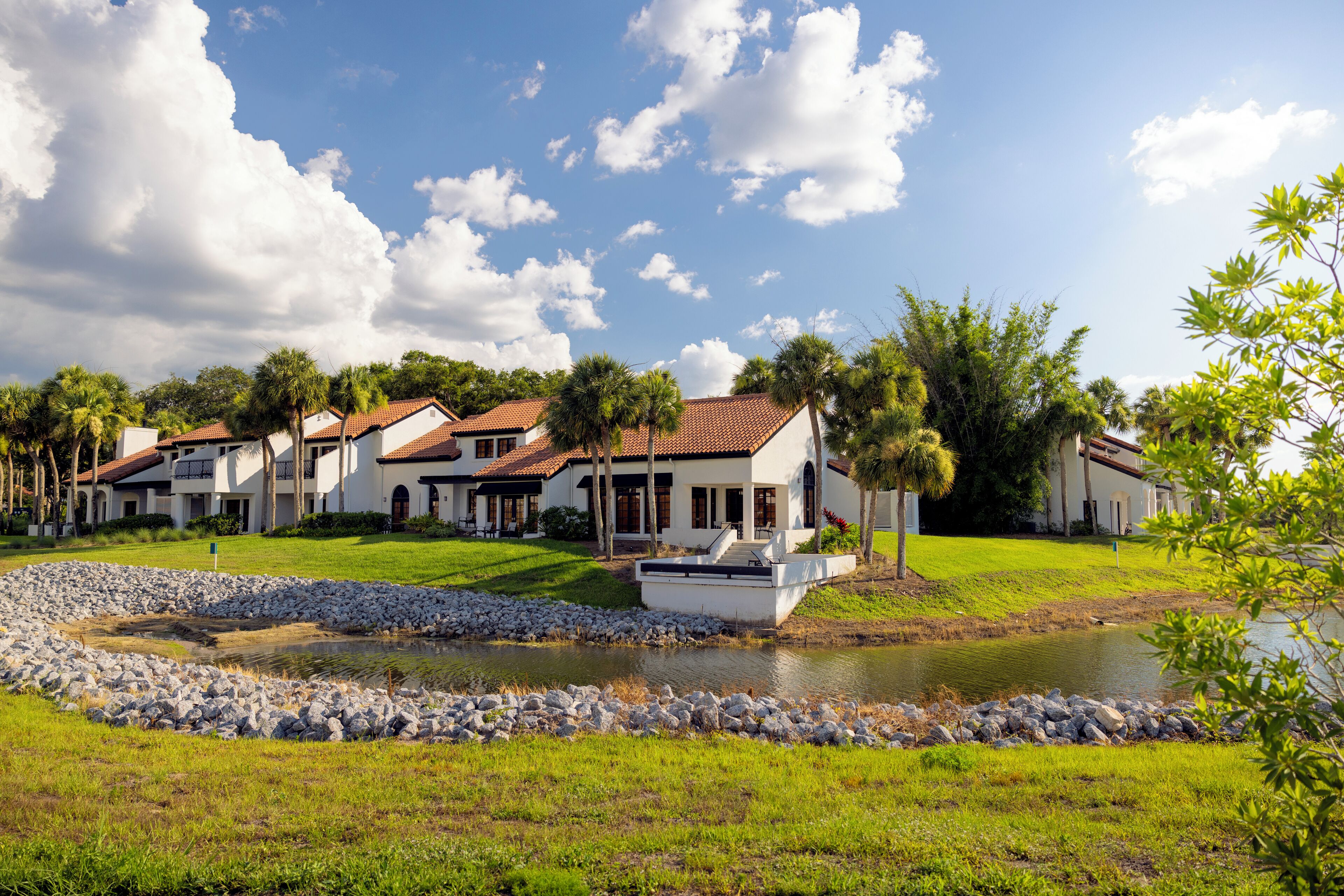 A residential area with multiple houses, a small pond, and a clear sky.