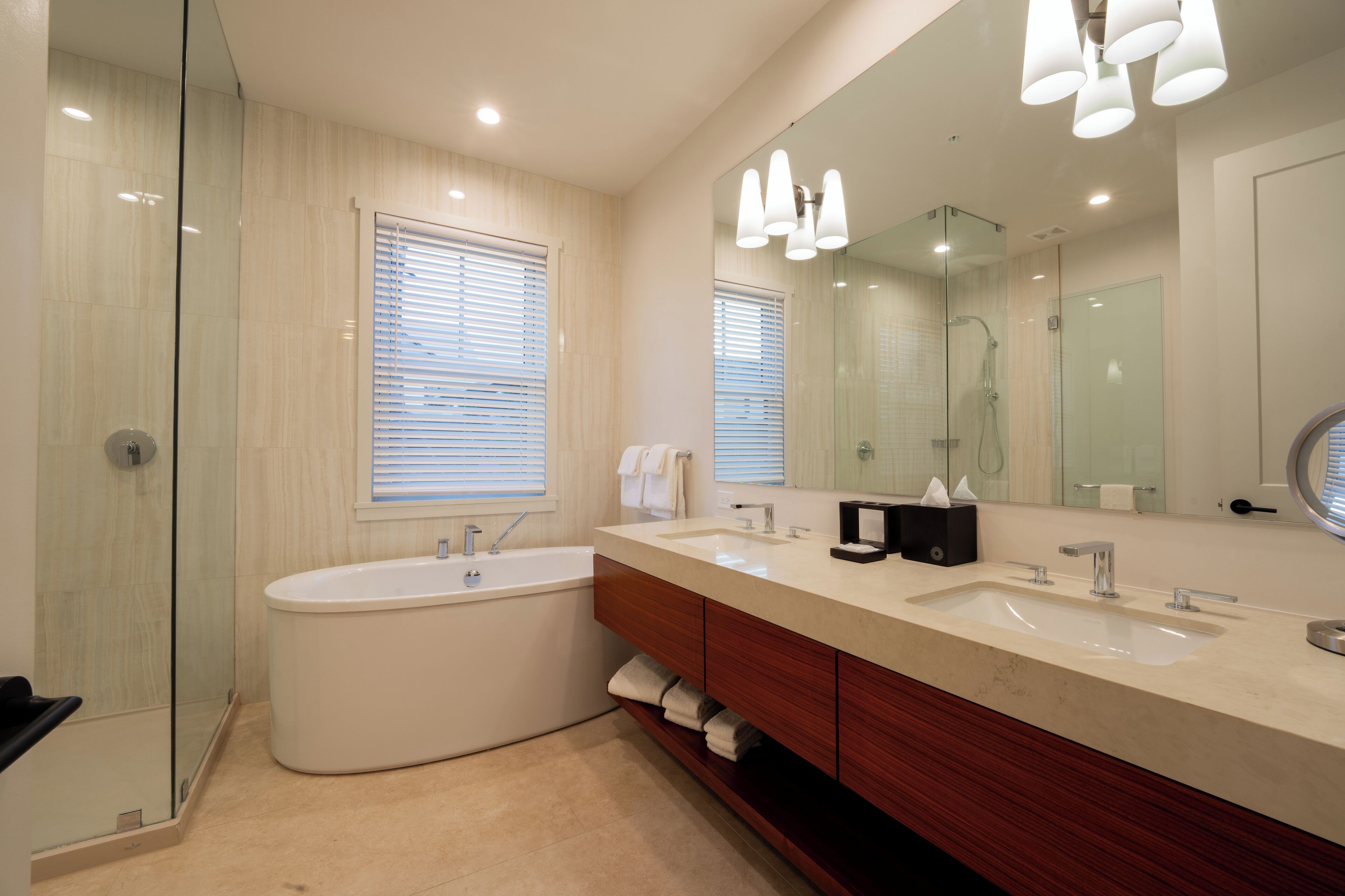 A modern bathroom with a freestanding bathtub, a double sink vanity, and a large mirror.