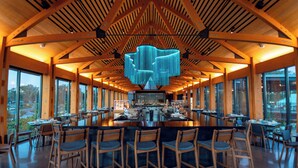 A spacious restaurant with a high ceiling, wooden beams, and a central bar area with stools. - Evermore Orlando Resort (Orlando)